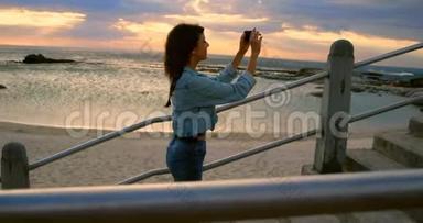 女人用<strong>手机点击</strong>海滩4k的照片